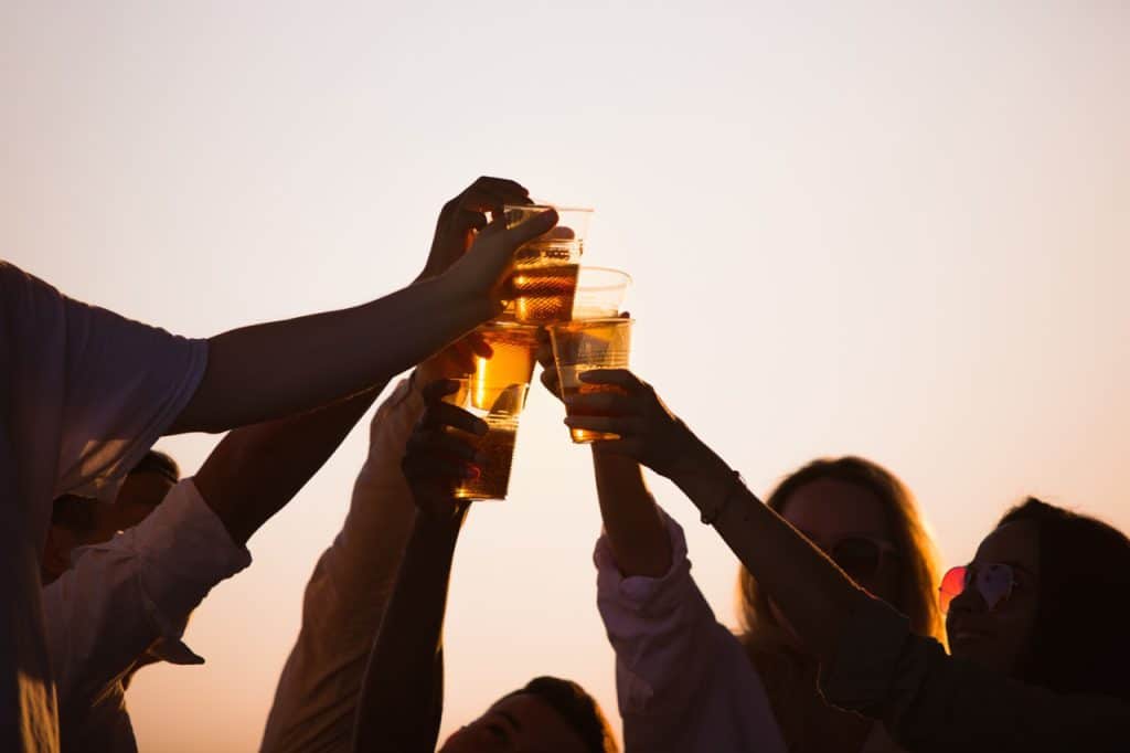 group of friends clinking beer glasses beach 1024x682 1